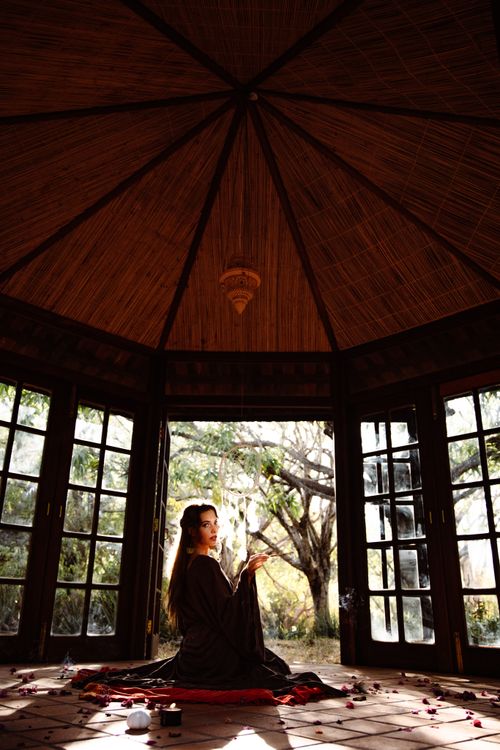 Free Woman meditating in a lighted gazebo surrounded by incense smoke, creating a serene atmosphere. Stock Photo