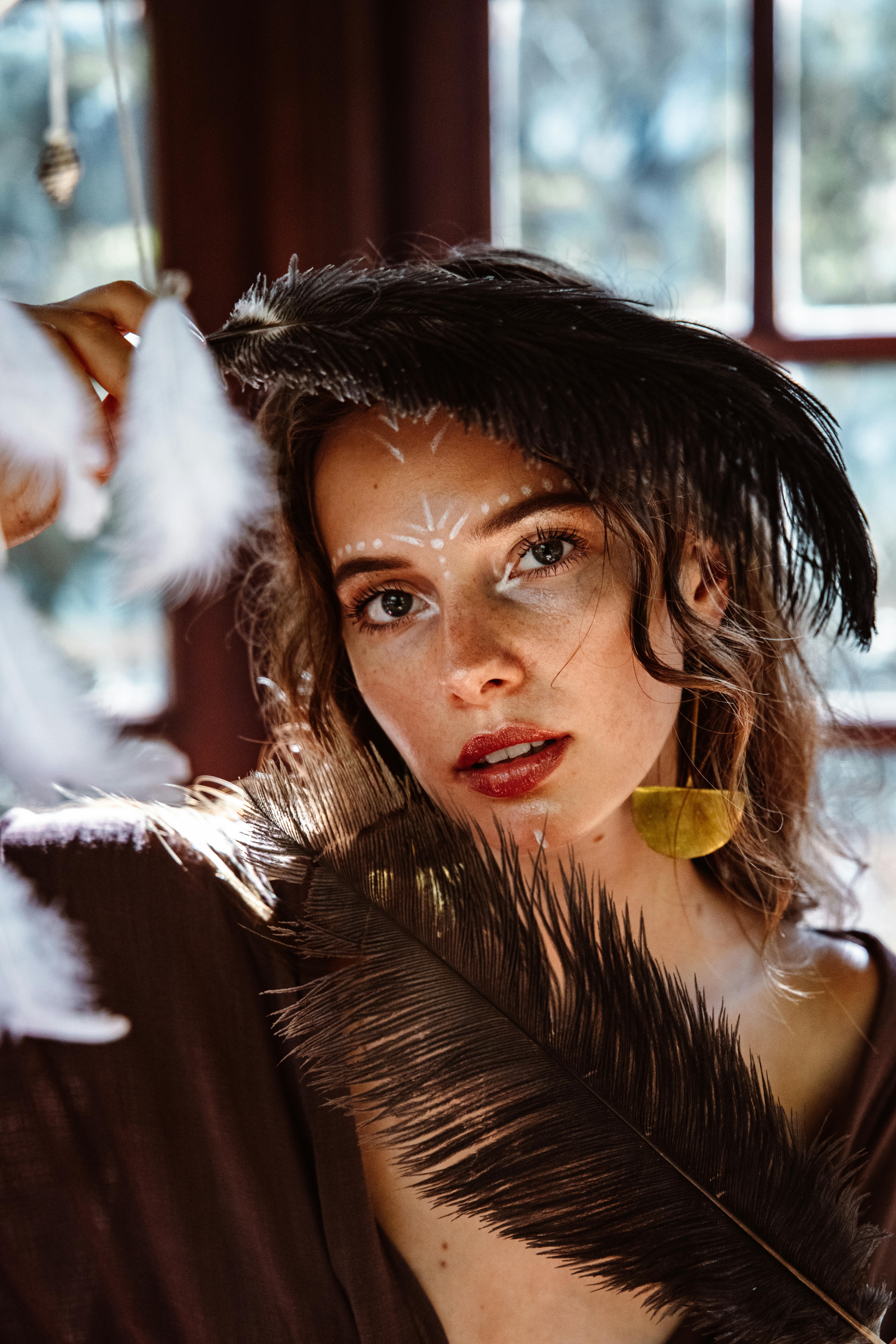 Captivating woman adorned with feathers in artistic pose, evoking sensual hypnotic tease and relaxed anticipation