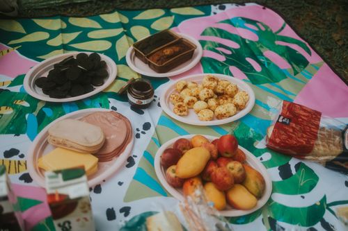 Free Vibrant picnic layout with fruits, snacks, and patterned blanket outdoors. Stock Photo