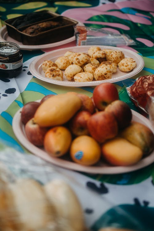 Plates with Exotic Fruits and Cookies on Table