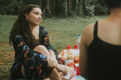 Free A woman enjoying a picnic outdoors, smiling and relaxed on a sunny day. Stock Photo