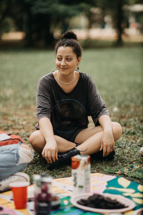 Free A woman relaxing during a summer picnic on a grassy area with drinks and snacks. Stock Photo