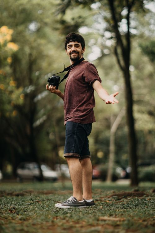 Free A cheerful man with a camera enjoys a sunny day in the park. Stock Photo