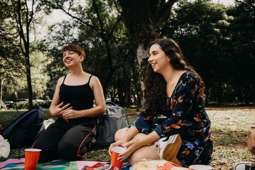 Free Two women enjoying a picnic and laughing together in a sunlit park setting. Stock Photo