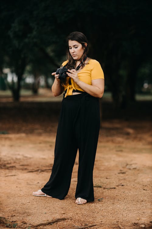 Free Woman in Yellow T-shirt and Black Pants Holding Black Dslr Camera Stock Photo
