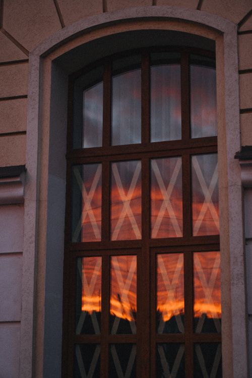 Free Beautiful sunset reflection on a stylish arch window with glass panels in modern architecture. Stock Photo