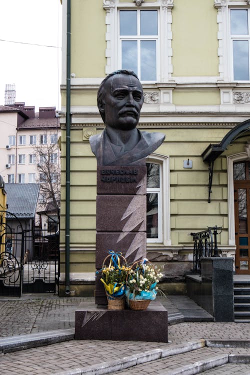 Bronze Statue of a Man in front of a Building in City 