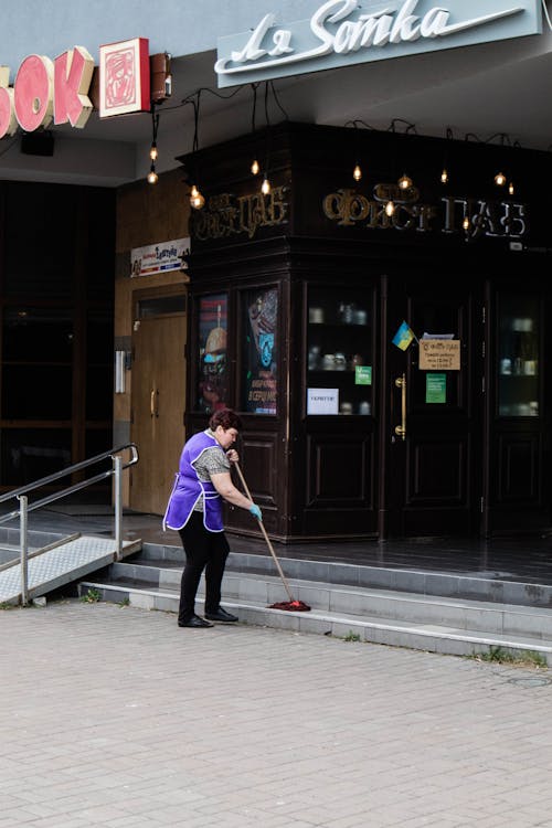 Free A Woman Mopping the Steps outside a Building Stock Photo