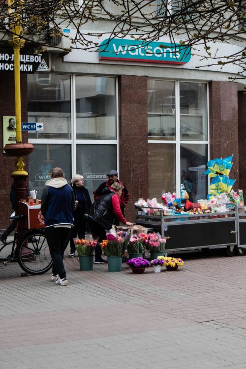 Free Street vendors display colorful flowers and products outside Watson store on a busy day. Stock Photo