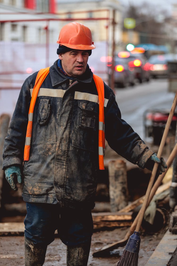 A Man With Mud On His Jacket And Rubber Boots