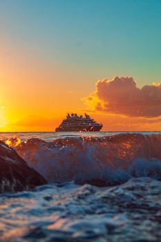 A cruise ship sailing at sunset with vibrant ocean waves in Grenada.