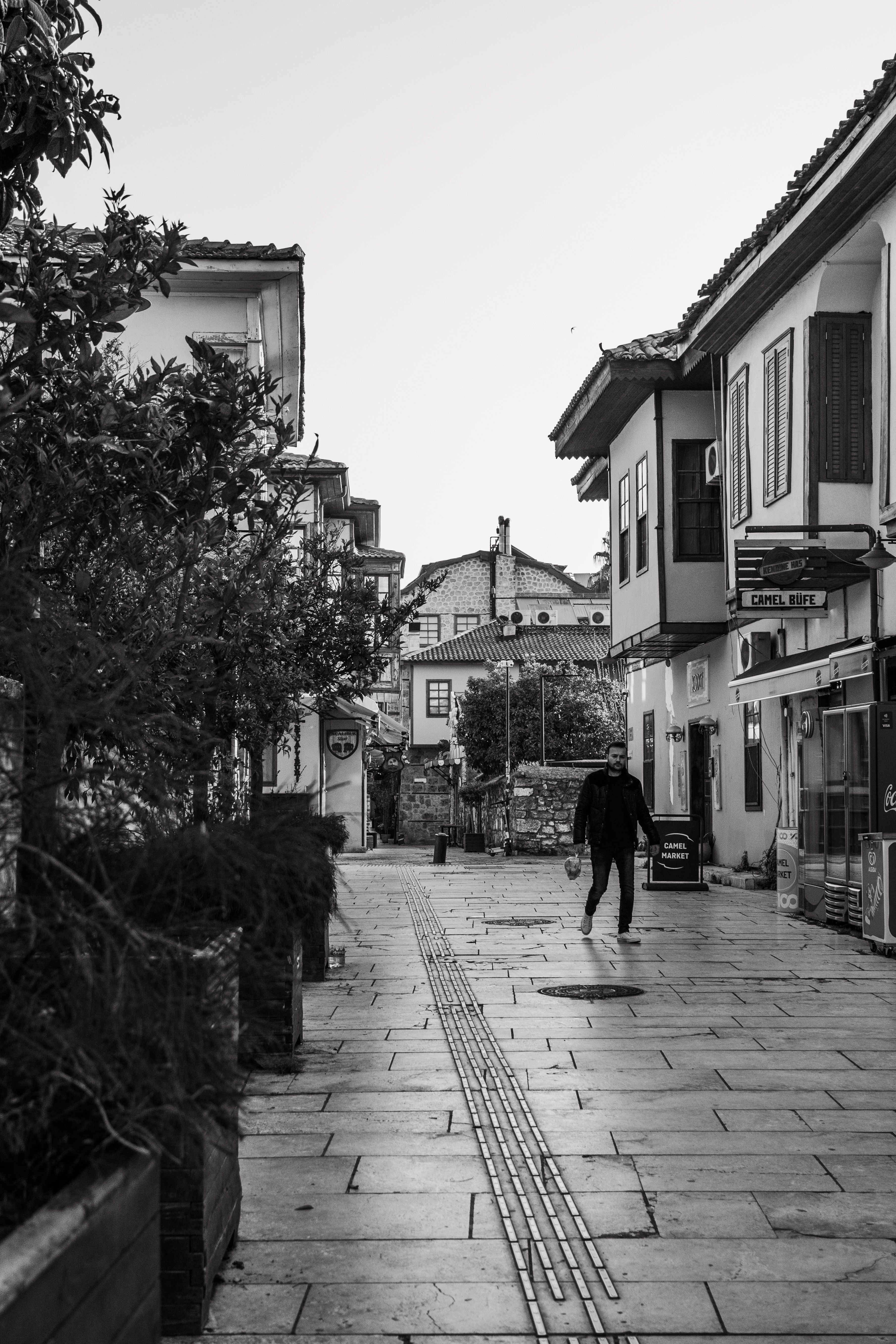 Grayscale Photo of Person Walking on Sidewalk · Free Stock Photo