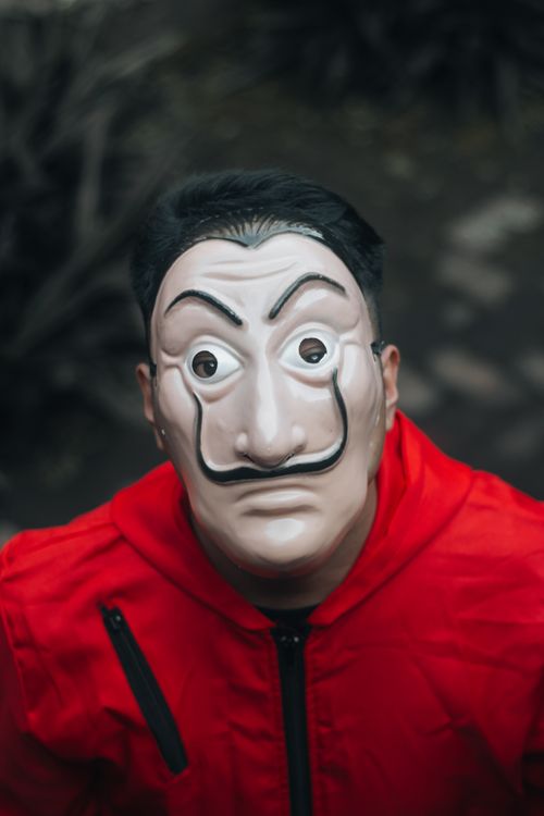 Free A person wearing a distinctive mask and red hoodie with an intense gaze. Stock Photo