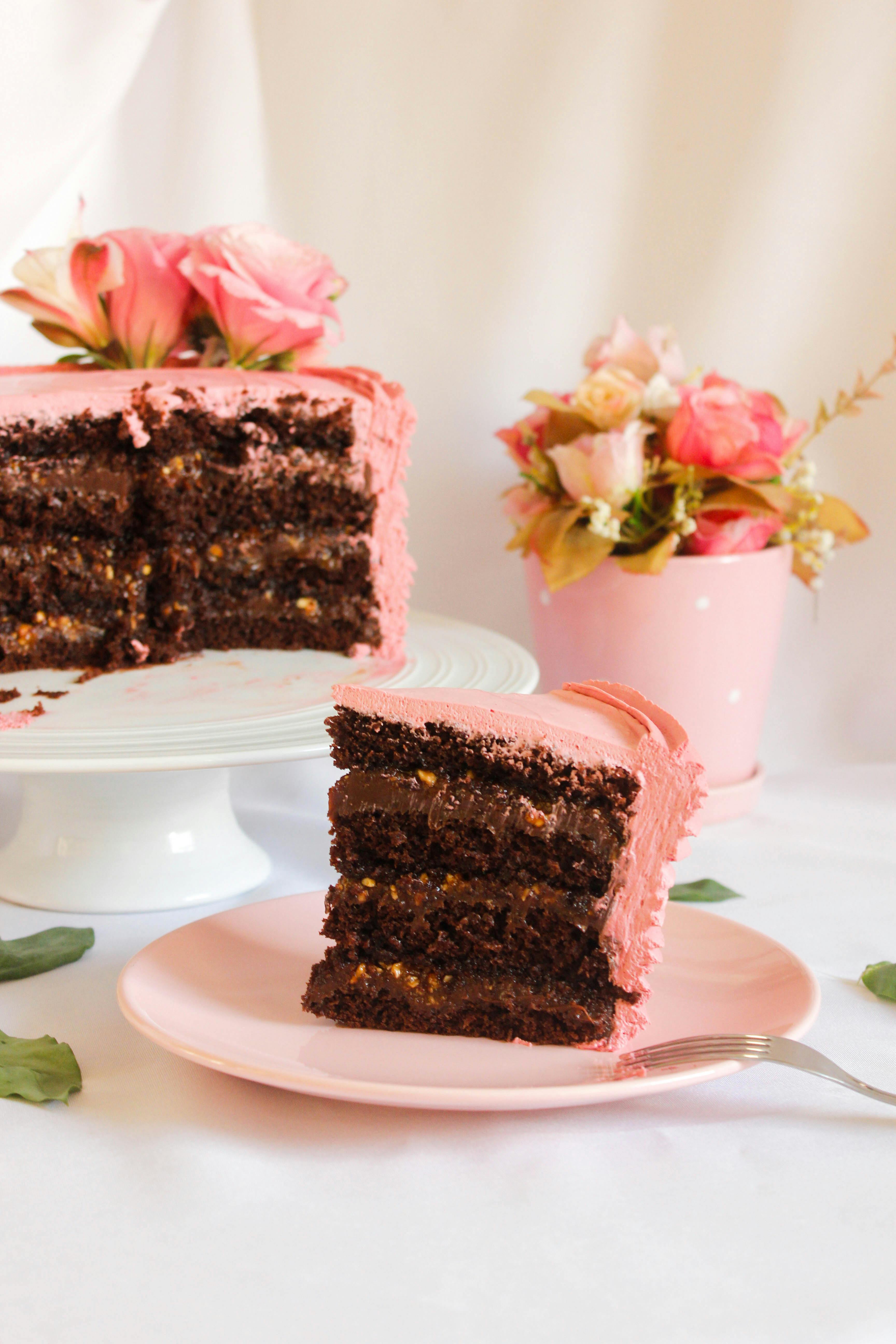 Indulgent chocolate cake with pink frosting, adorned with fresh roses, perfect for dessert lovers.