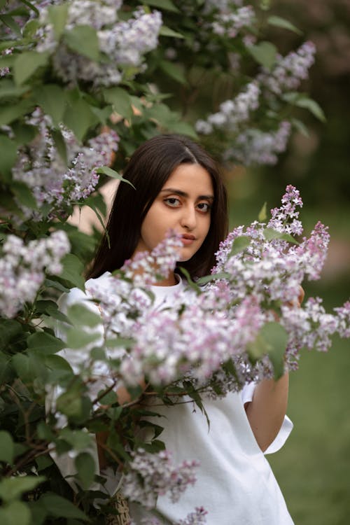 Woman in White Dress Holding Purple Flowers