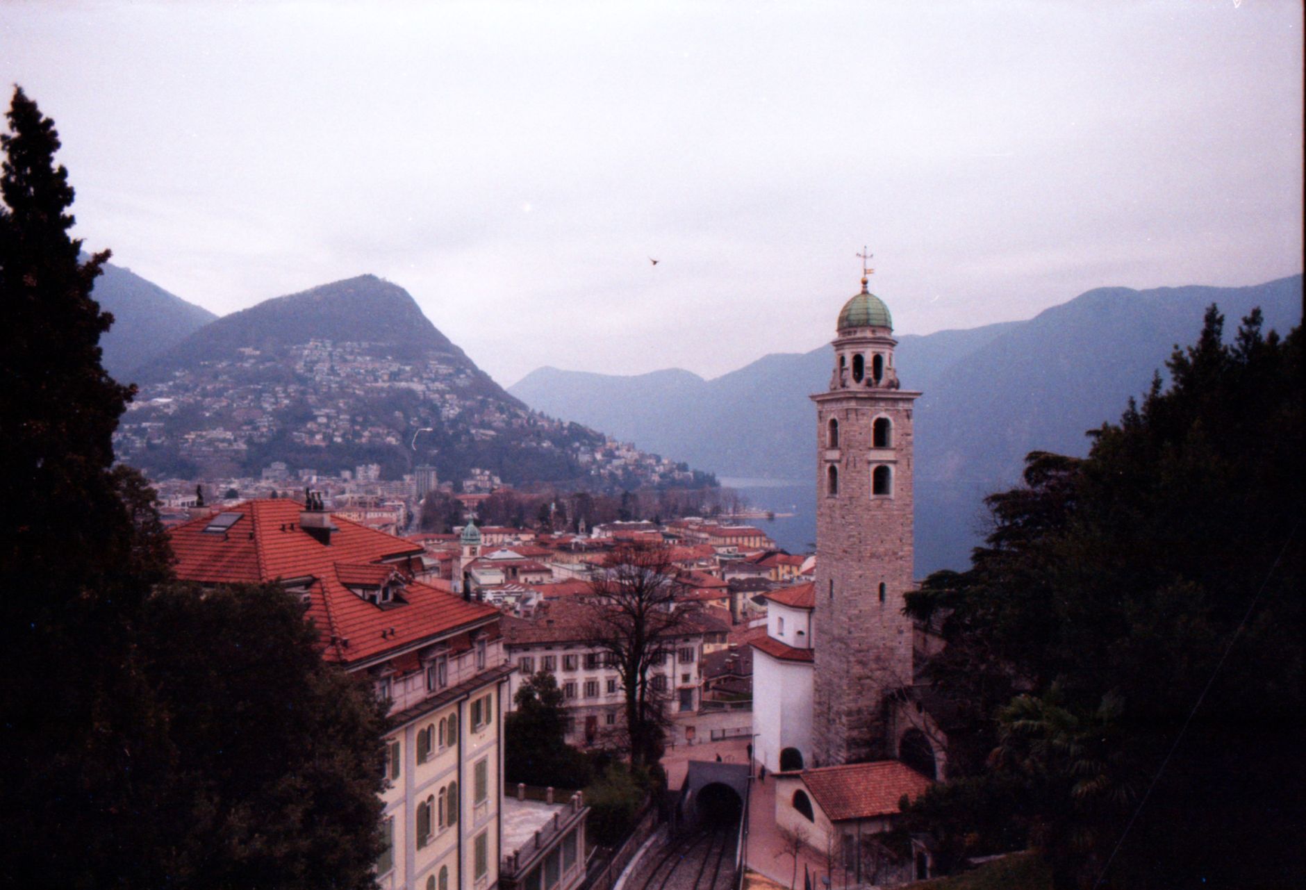 Beautiful view of Lugano with its iconic cathedral tower amidst mountain backdrop.
