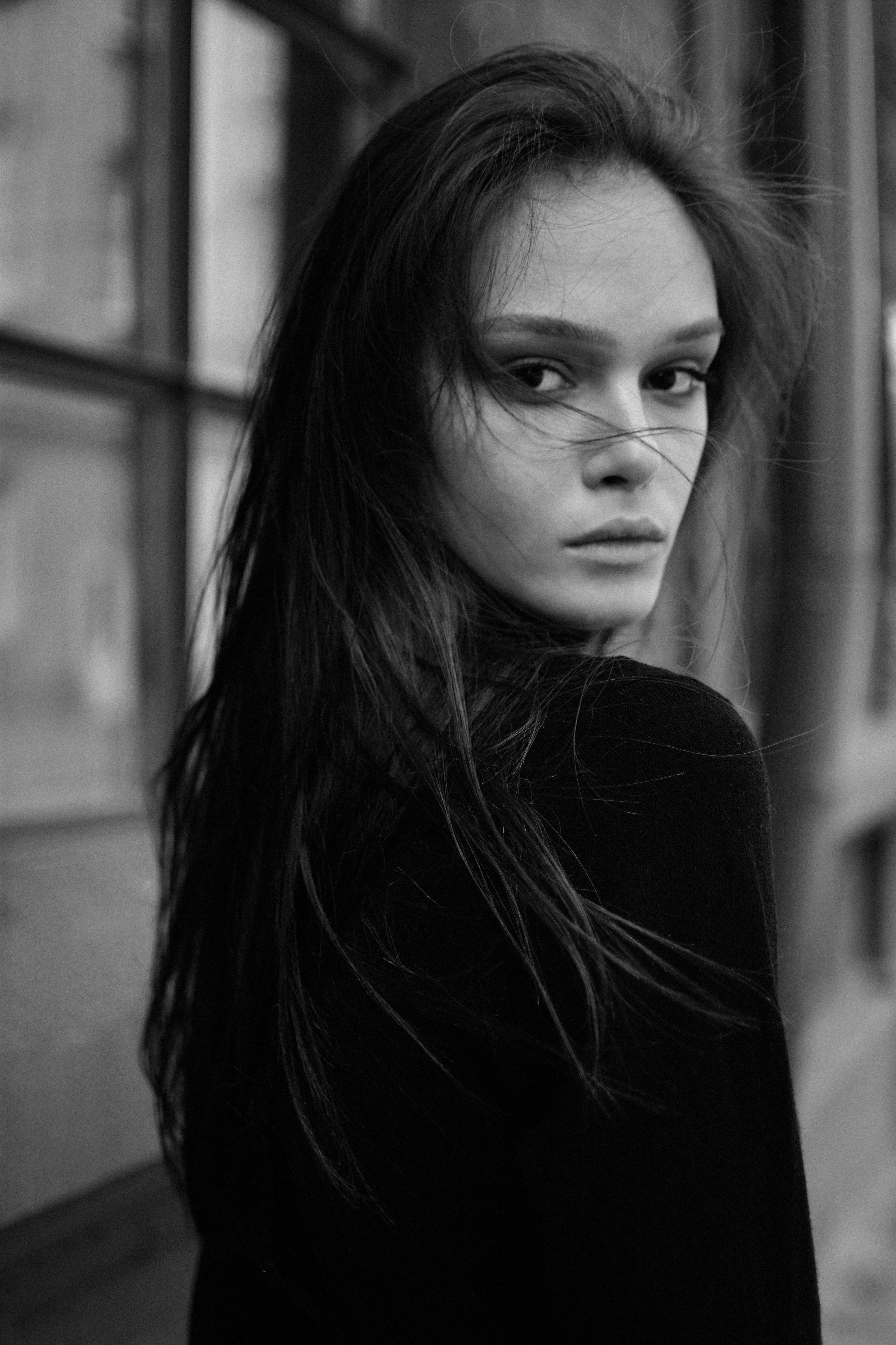 Moody black and white outdoor portrait of a woman with flowing hair.