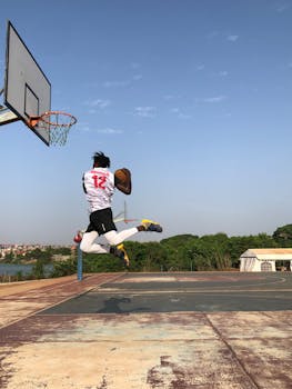 Athlete performs an impressive basketball dunk on an outdoor court in Conakry, showcasing skill and determination.