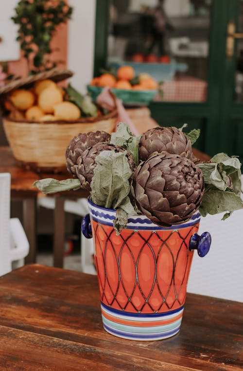 Artichokes in a Ceramic Vase on Wooden Table 