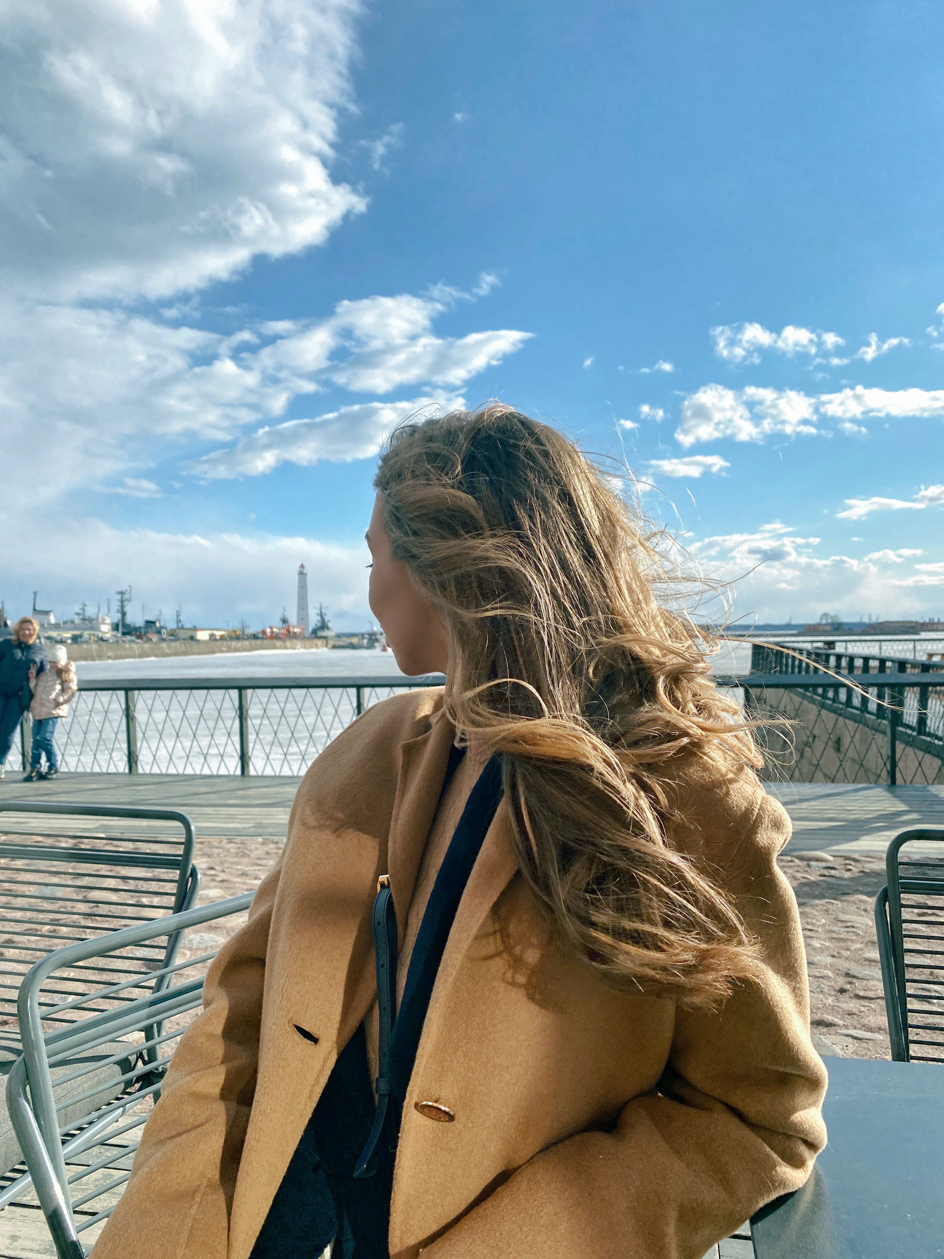 Woman in Brown Coat Sitting While Looking Back · Free Stock Photo