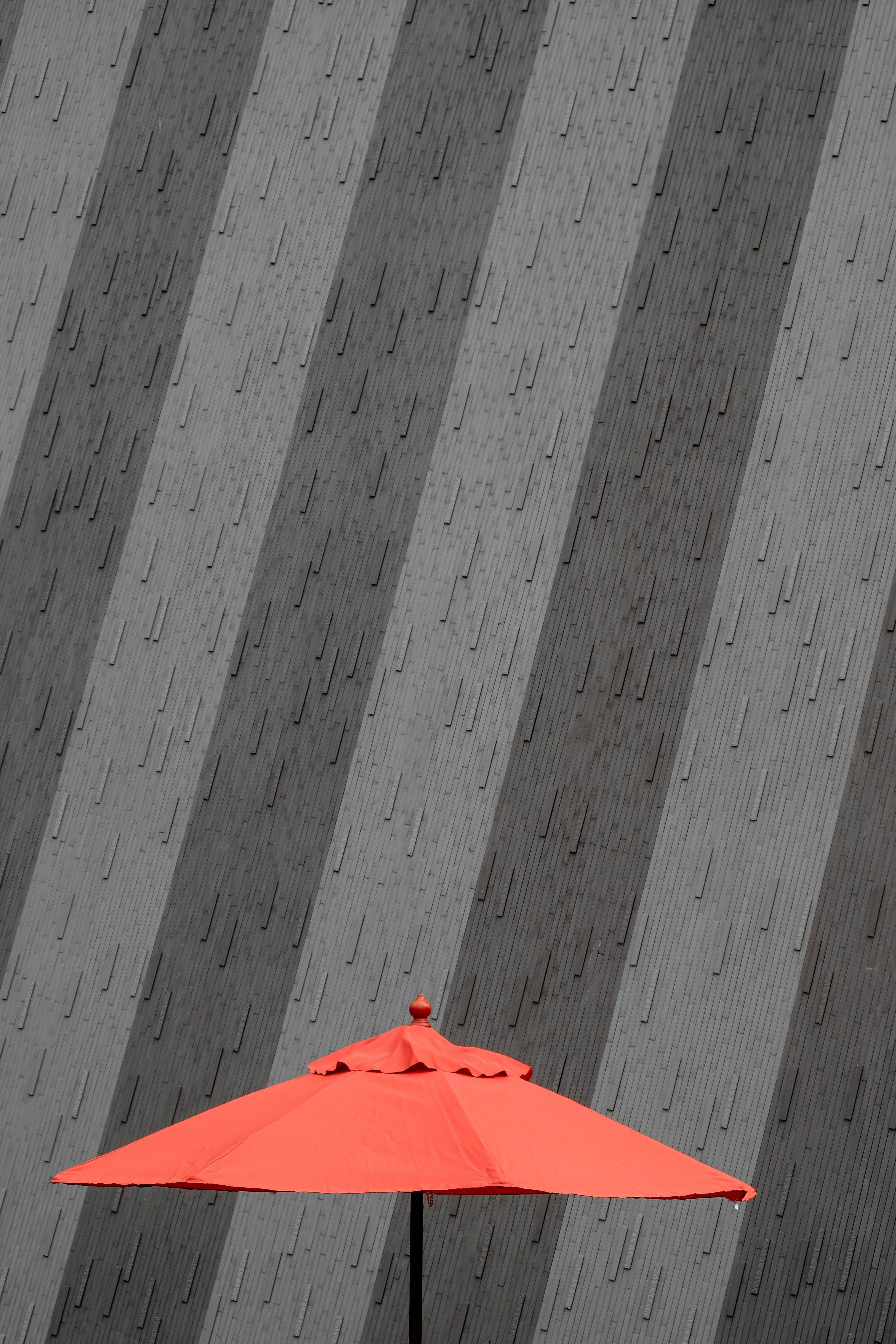 大胆的红色伞与灰色墙壁上极简风格的几何图案形成鲜明对比