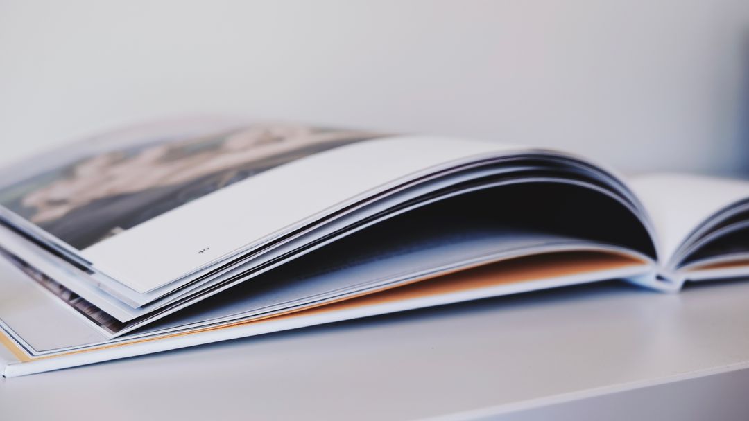 Close-up of an open magazine lying on a white surface, showcasing glossy pages.