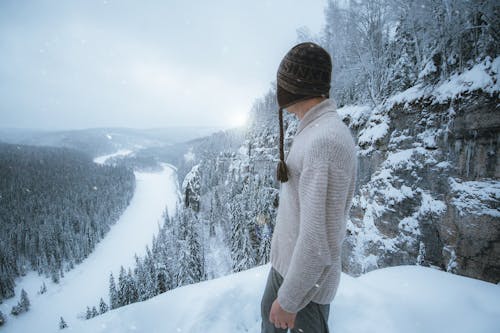 Man in Knitted Sweater standing on a Cliff during Winter 
