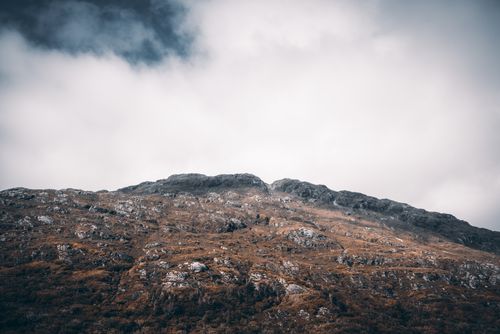 Free A stunning rocky mountain under a thick cloudy sky, showcasing the beauty of untouched nature. Stock Photo