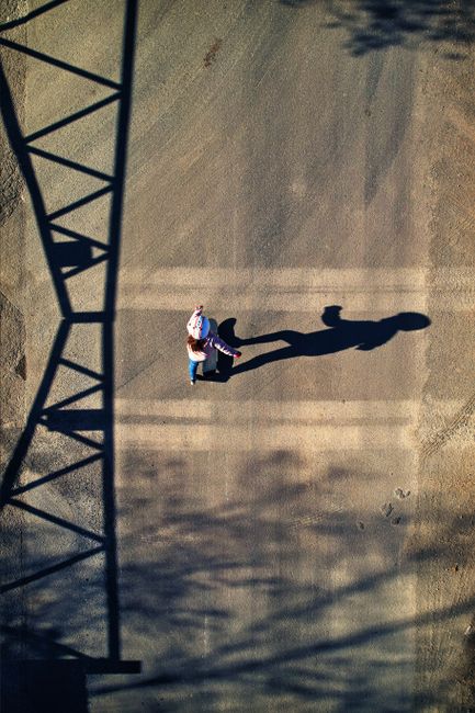 Aerial shot of a skateboarder casting a long shadow on an empty road in Rockbeare, England.