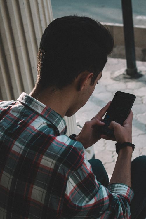 Free Adult man in plaid shirt using a mobile phone outdoors, capturing casual communication Stock Photo