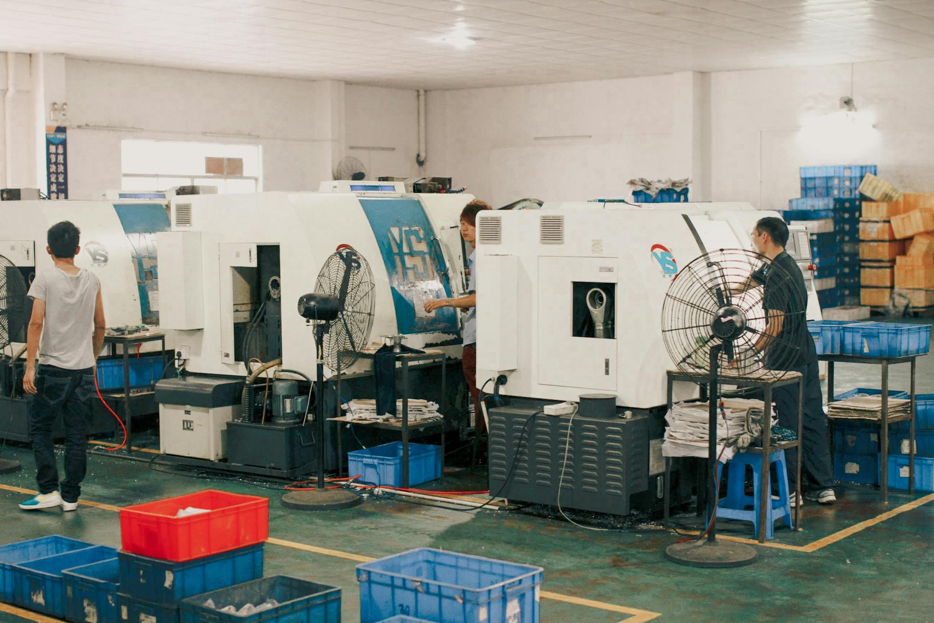 Workers operating machinery in an industrial factory setting, showcasing manual labor and production.