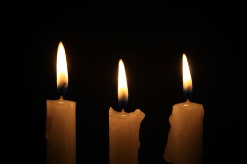 Free Three lit candles illuminate the darkness with a warm glow, creating a serene and intimate ambiance. Stock Photo