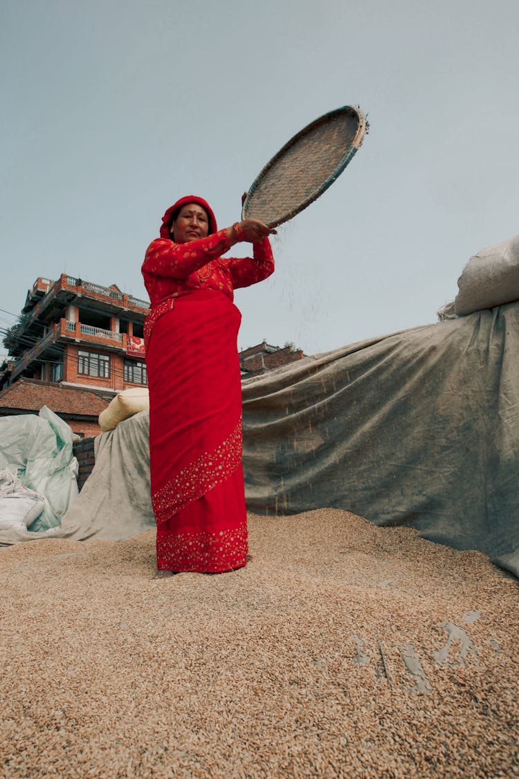 Woman In Red Dress Spilling Grain