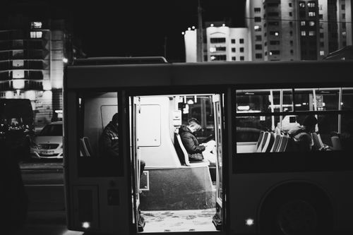 Free Black-and-white photo of commuters inside a bus at night. Urban setting. Stock Photo
