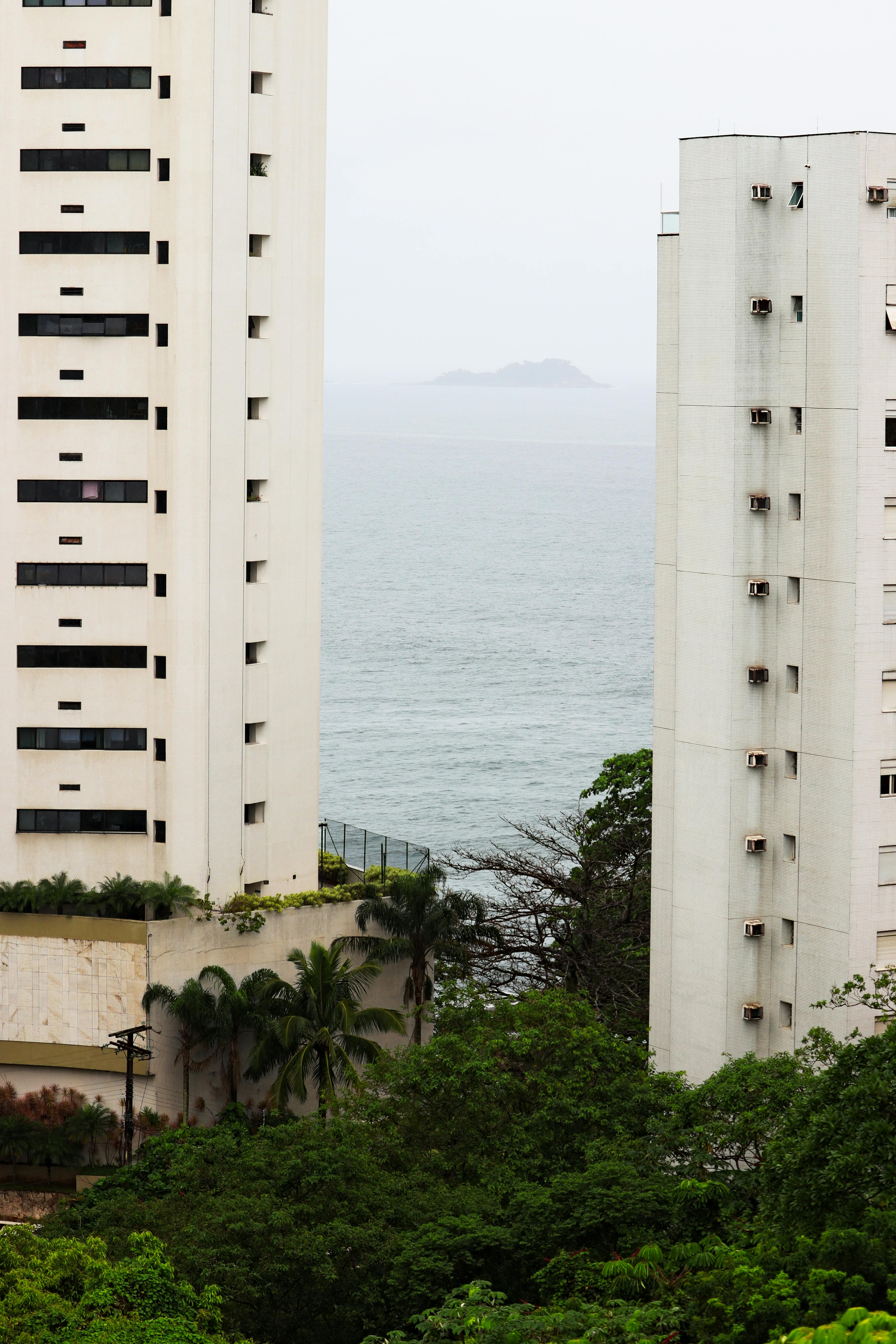A coastal view framed by tall buildings and lush greenery in São Paulo, Brazil.