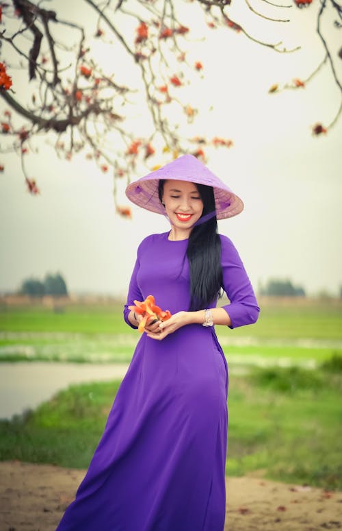 Free Woman in Purple Dress Standing on Grass Field Stock Photo