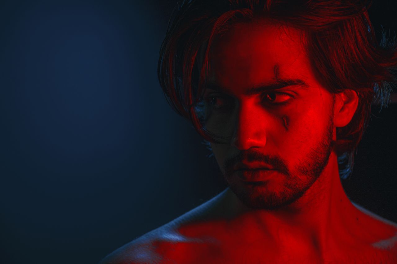 close up portrait of a man in red and blue lighting creating a dramati
