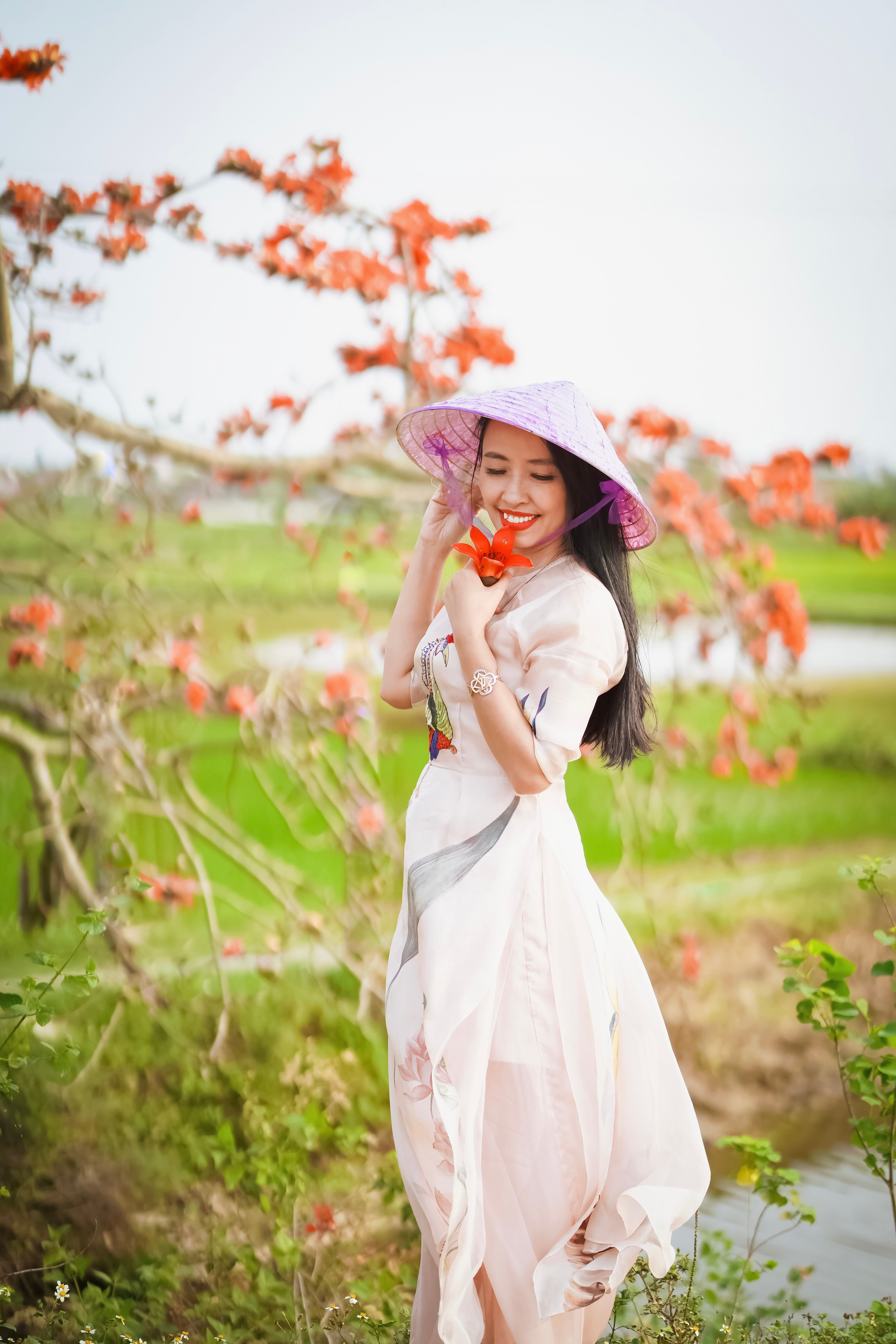 A Woman Wearing Floral Dress and a Straw Hat Holding Flowers from the ...