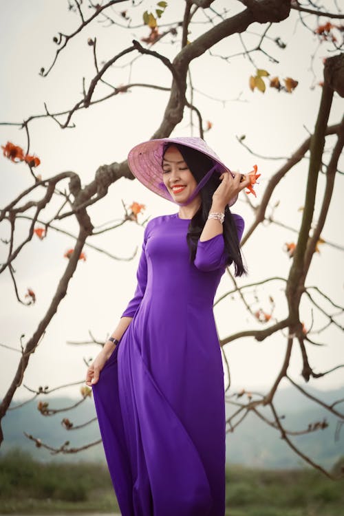 Smiling Woman Wearing Purple Dress and a Conical Hat