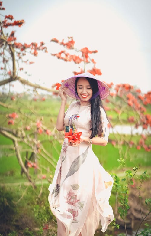 Smiling Woman Wearing a Floral Dress and a Conical Hat