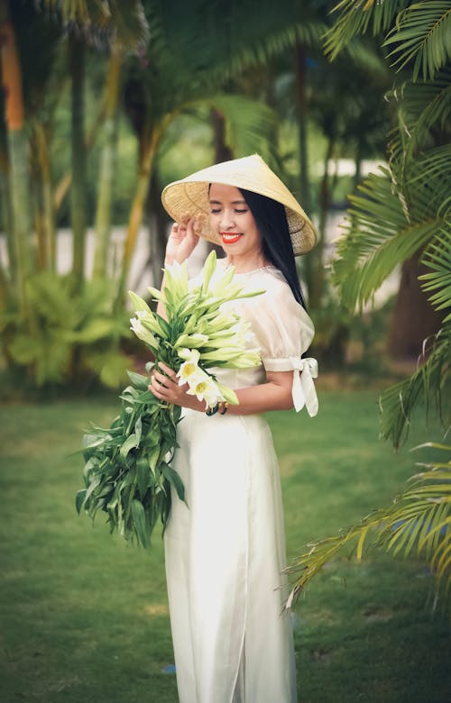 Woman in White Dress Holding a Bouquet of White Flowers