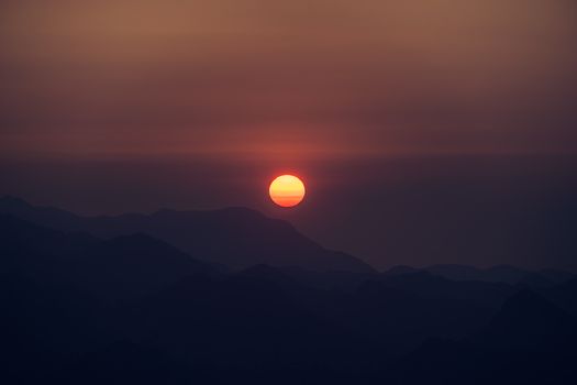 Beautiful sunset casting a warm glow over mountain silhouettes, creating a tranquil and serene atmosphere.