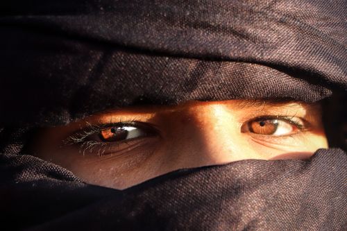 Free Captivating eyes peering from a traditional hijab in the Algerian sun. Stock Photo
