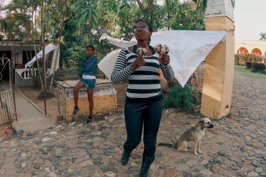 A woman with sunglasses plays maracas in an outdoor setting, exuding casual style and energy. — photo by Mehmet Turgut  Kirkgoz