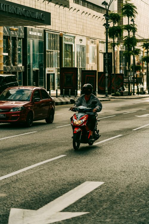 Free Motorcyclist rides through the bustling streets of Kuala Lumpur, Malaysia. Stock Photo