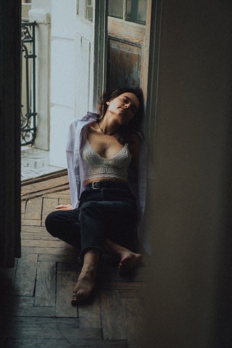 Woman Sitting On Hardwood Floor Leaning On Doors With Eyes Closed