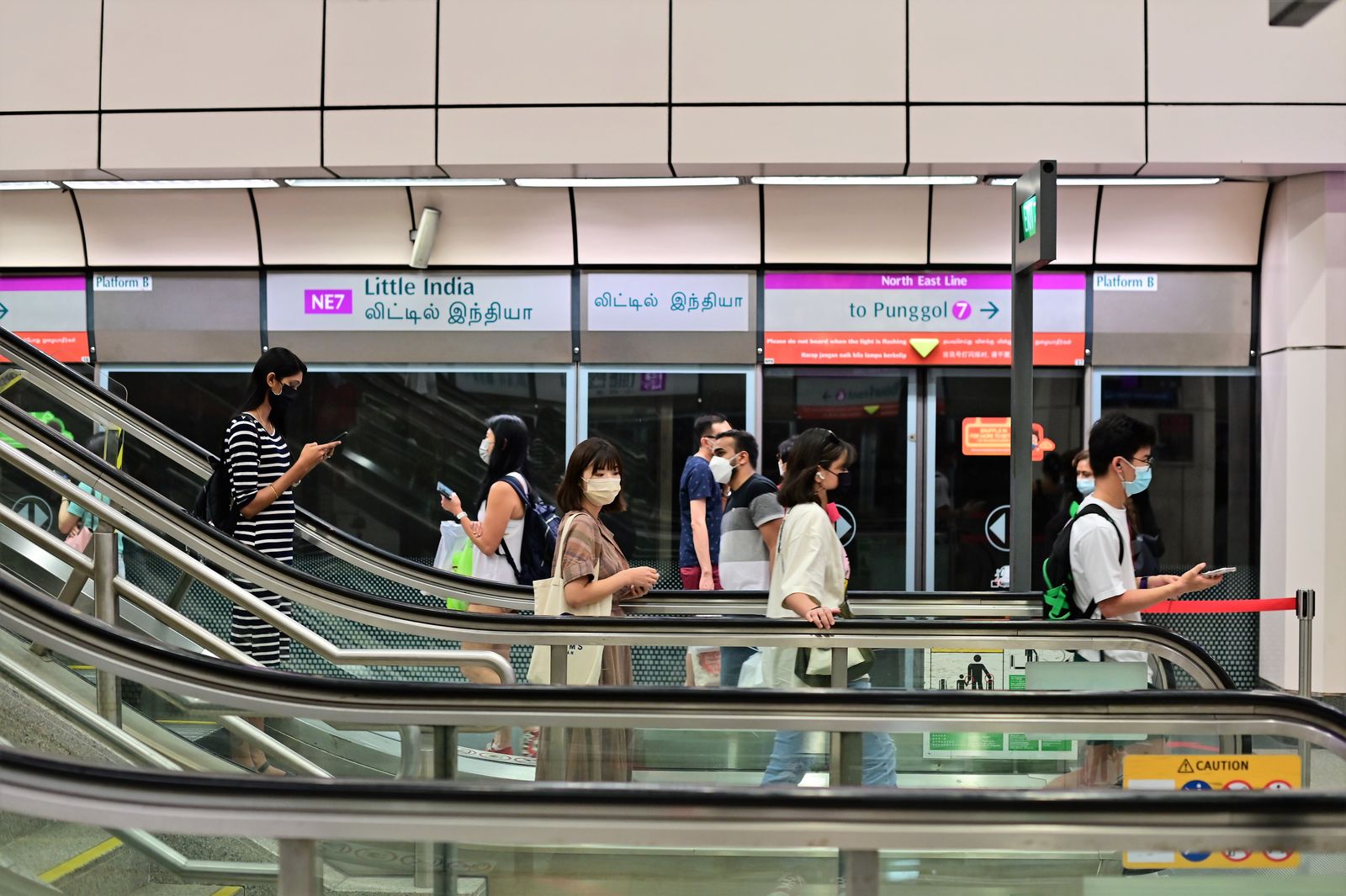 Passengers riding escalators inside a busy transit station