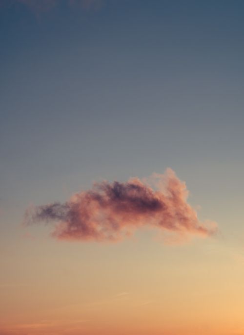 Free A peaceful view of a single cloud in a colorful sunset sky, perfect for nature and tranquility themes. Stock Photo