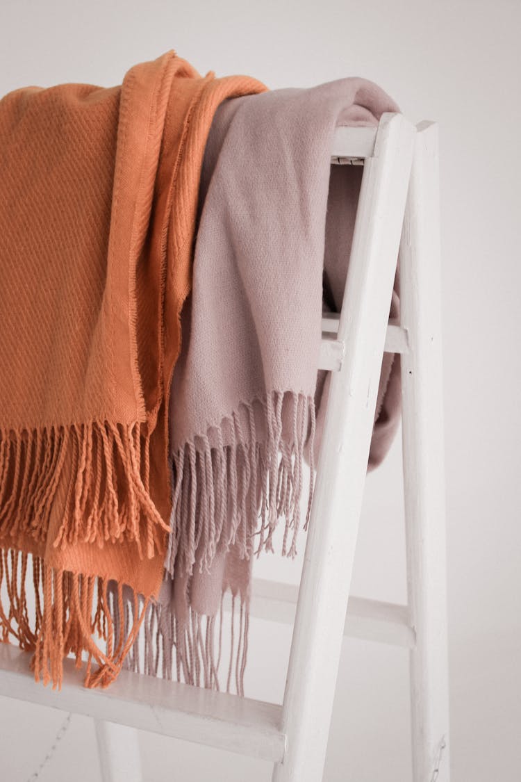 Folded Orange And Beige Scarves Hanging On A Rack