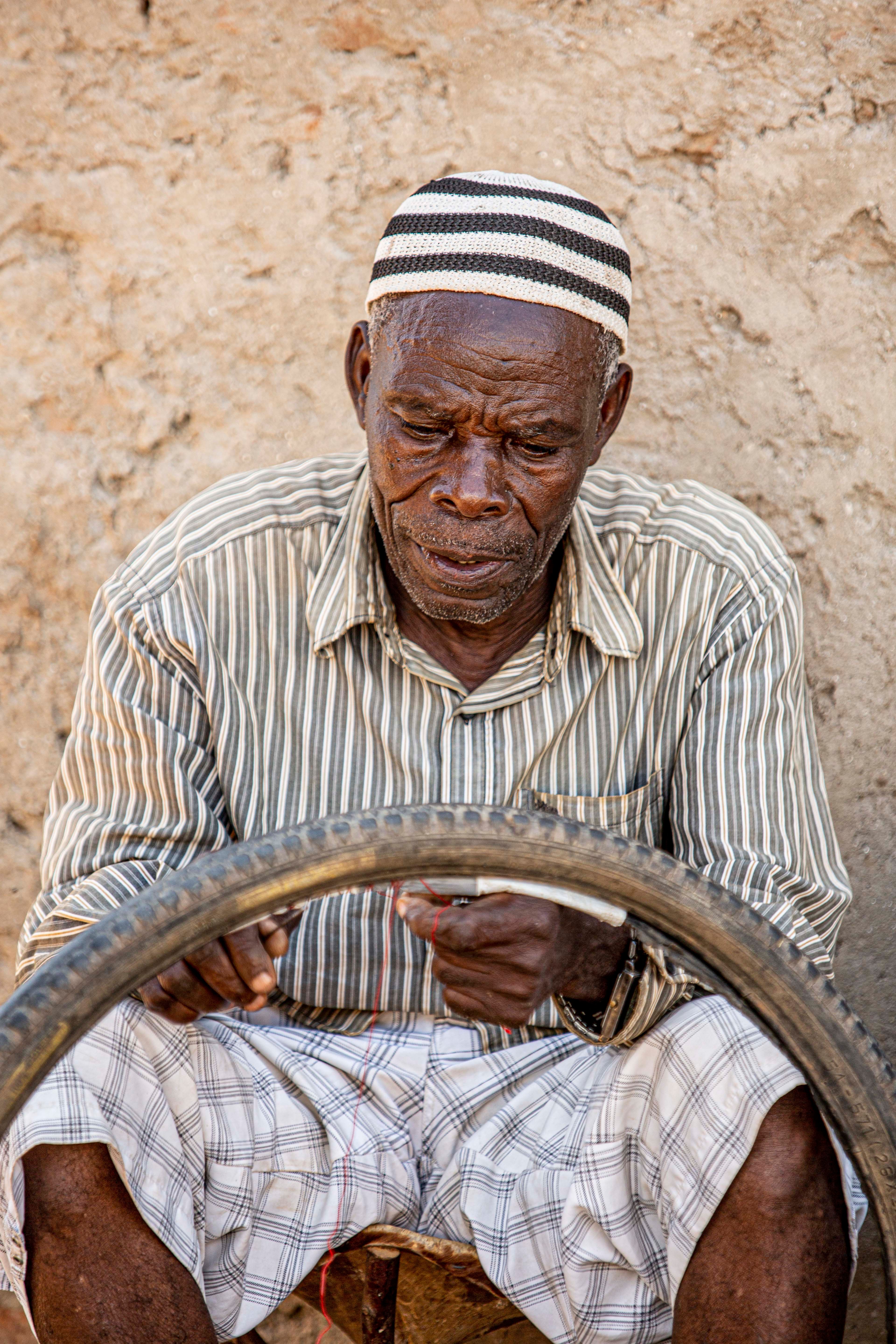 Senior man repairing a tire, showcasing traditional skills outdoors.